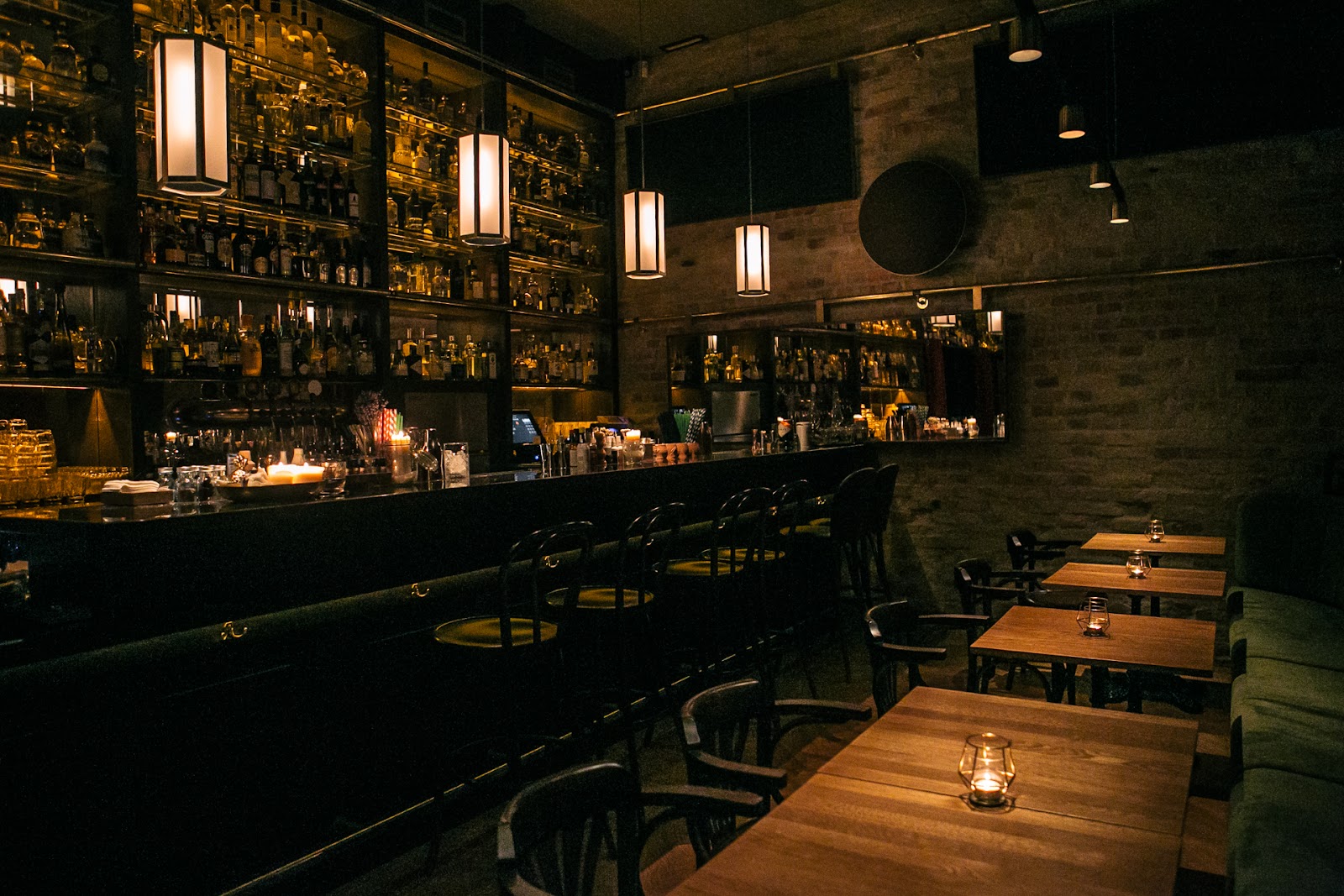 Hushed speakeasy bar with leather seating and low amber light, close in mood to Black Swan Lab Budapest