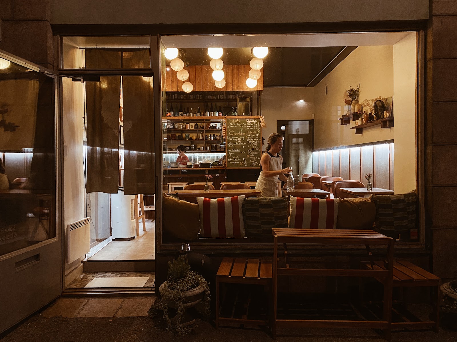 Small intimate bar with warm light and dark wood, similar in feel to Sake Bar and Izakaya Helsinki