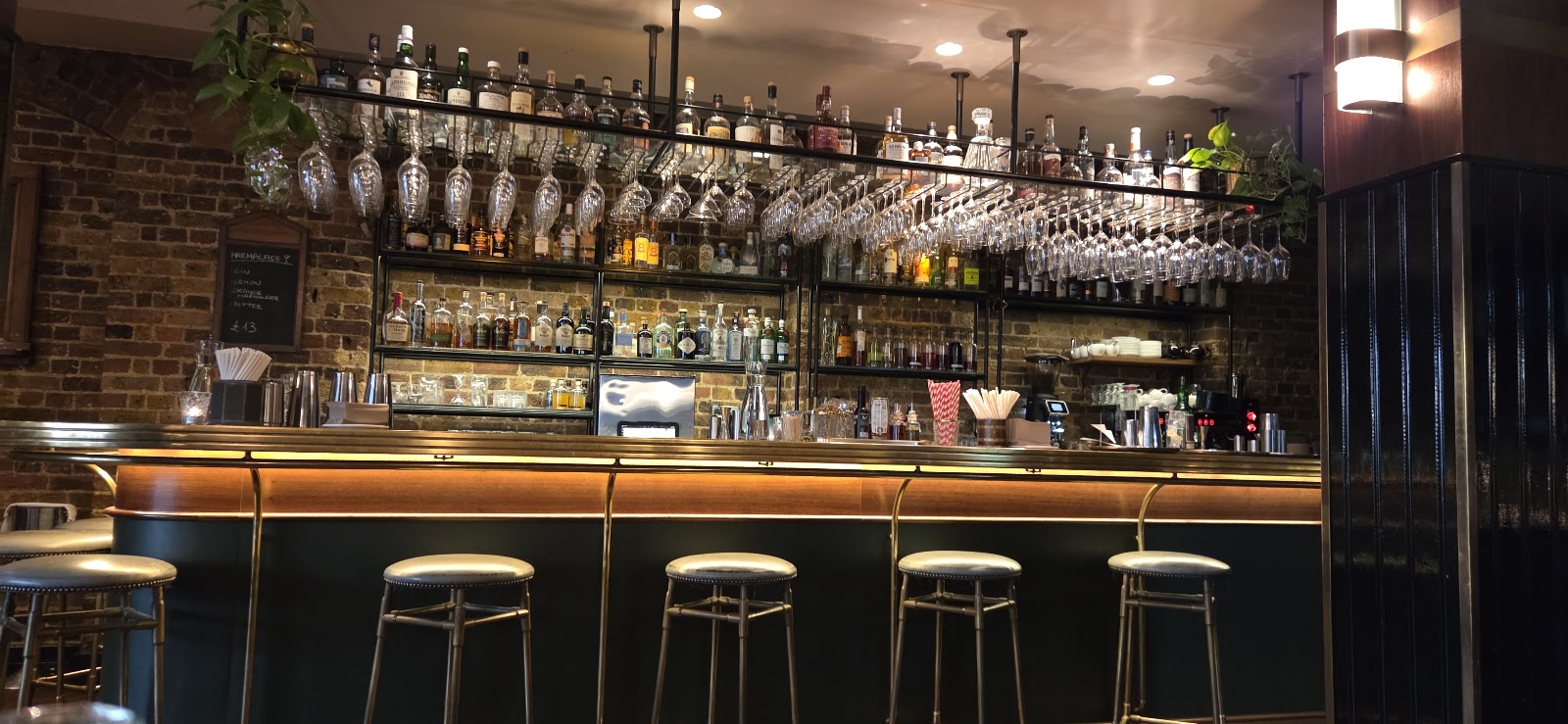 Low-lit basement cocktail bar with brass panelling and leather booths