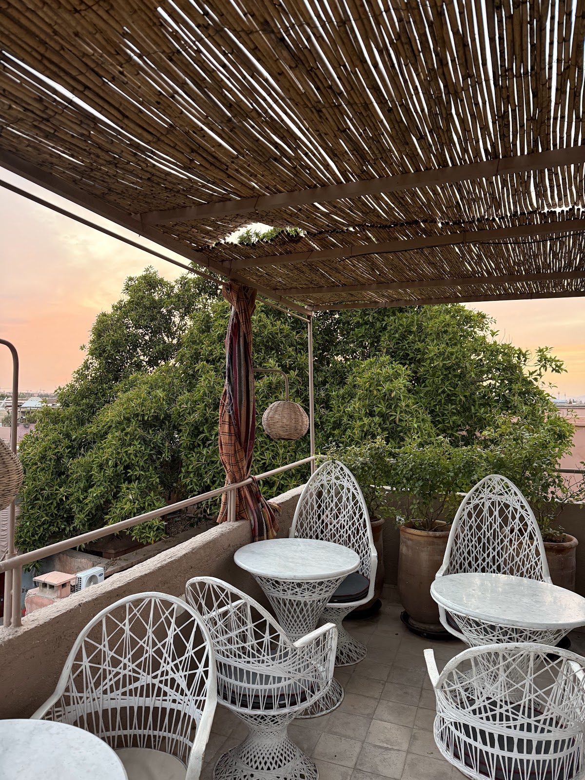 Open air rooftop terrace at dusk with warm string lights, similar in mood to Atay Cafe in the Marrakech medina