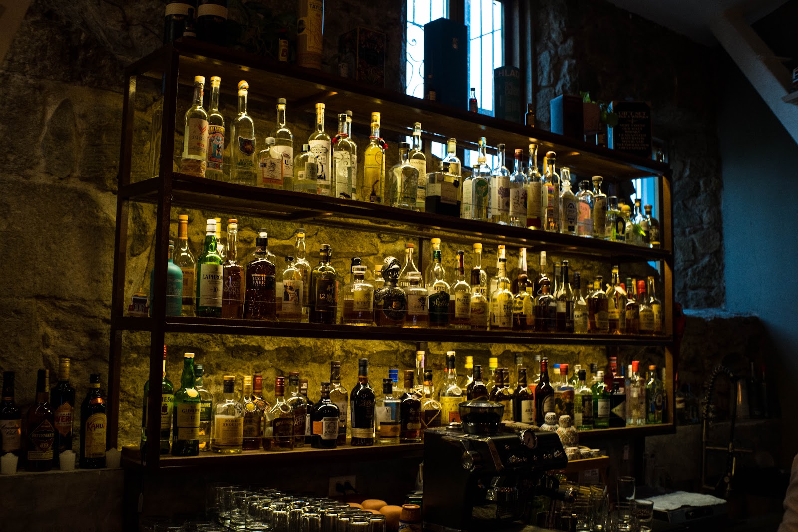 Dim speakeasy cocktail counter with a bartender mixing a drink