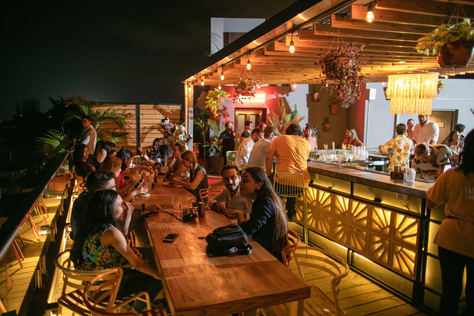 Colorful rooftop terrace bar with greenery and city views at golden hour