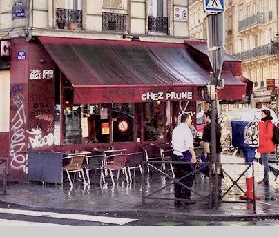 Corner cafe bar with a pavement terrace beside a Paris canal at dusk