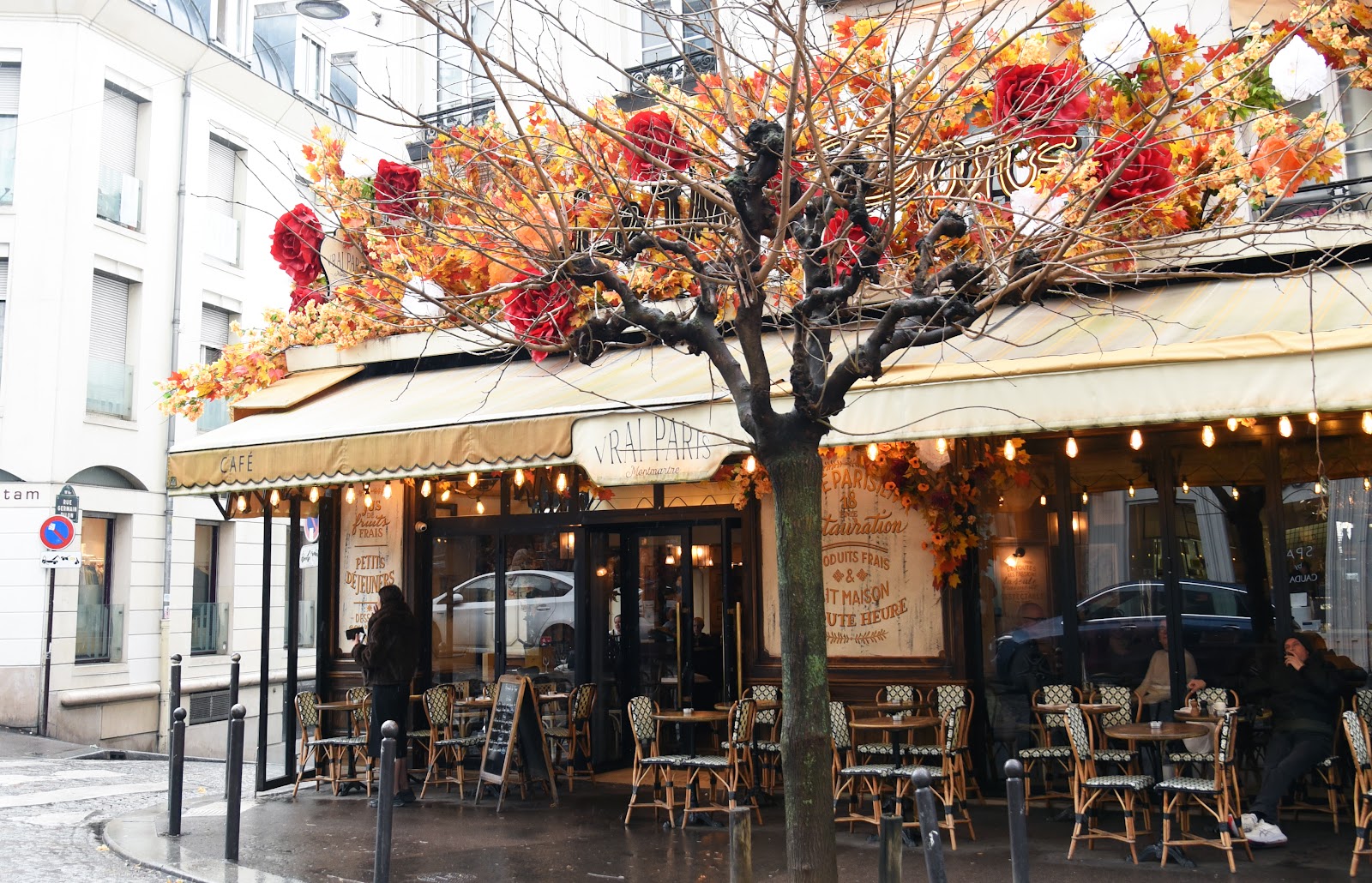 Pavement terrace and red awning of a classic Montmartre bistro on Rue des Abbesses, Paris