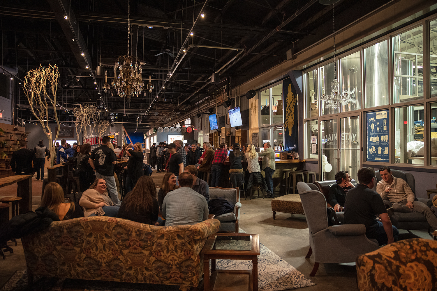 Large beer hall with long tables and screens in Philadelphia