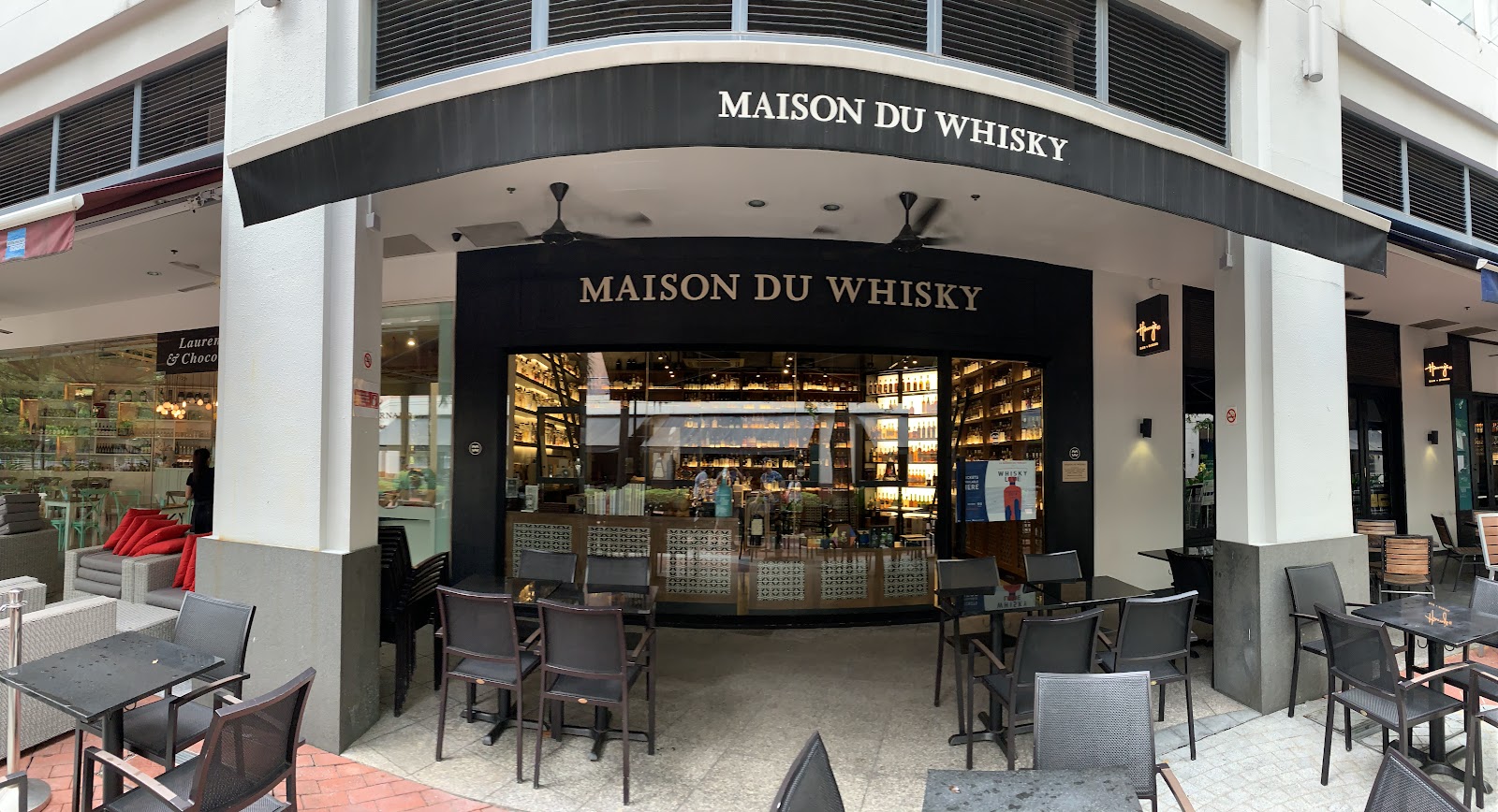 Backlit whisky bottles behind the tasting bar at La Maison du Whisky Singapore