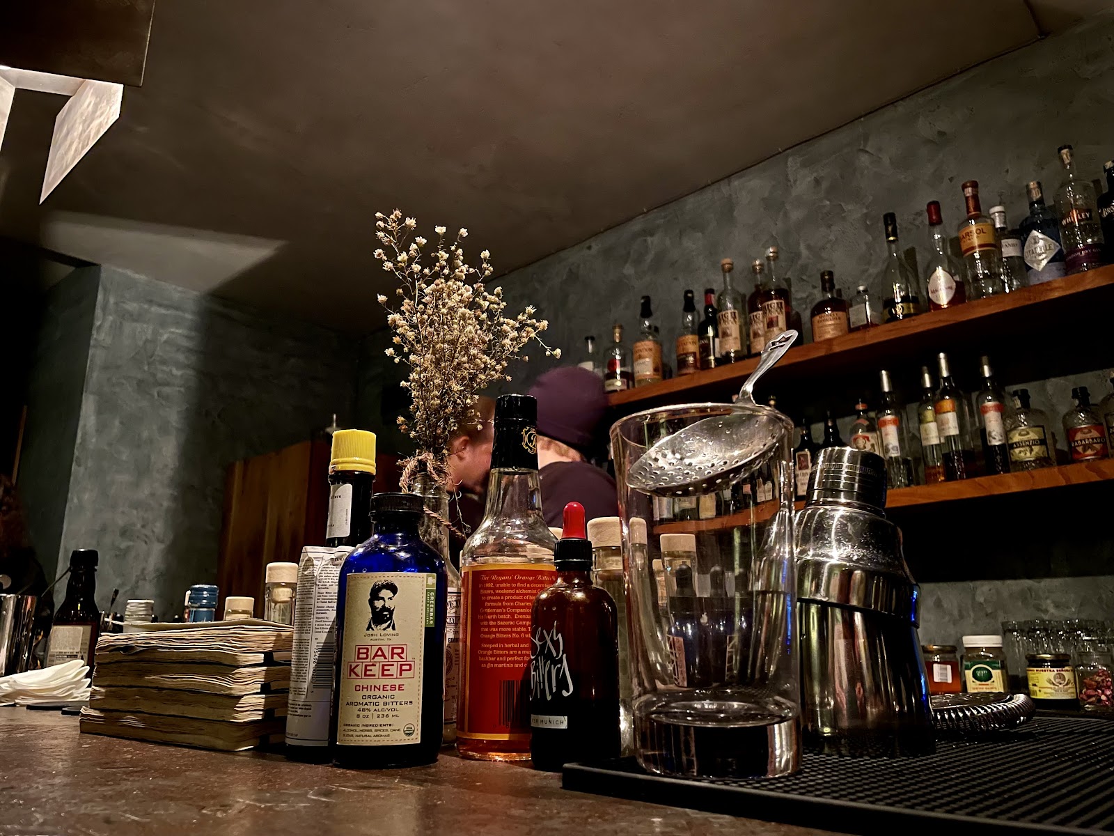 Low lit basement cocktail bar with bottles behind the counter